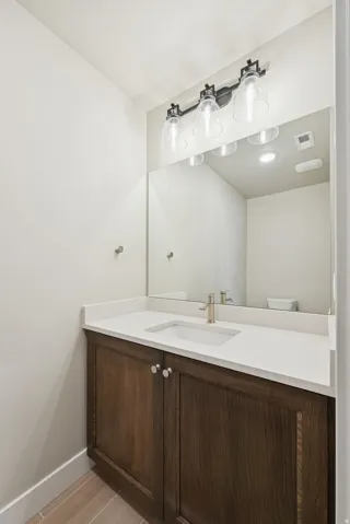 Vanity with wood-finish cabinetry, white countertop, and integrated sink