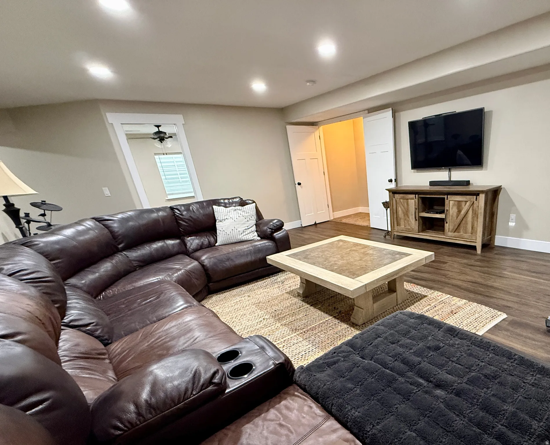 Spacious entertainment area featuring wood-finish flooring, recessed lighting, and a neutral wall palette