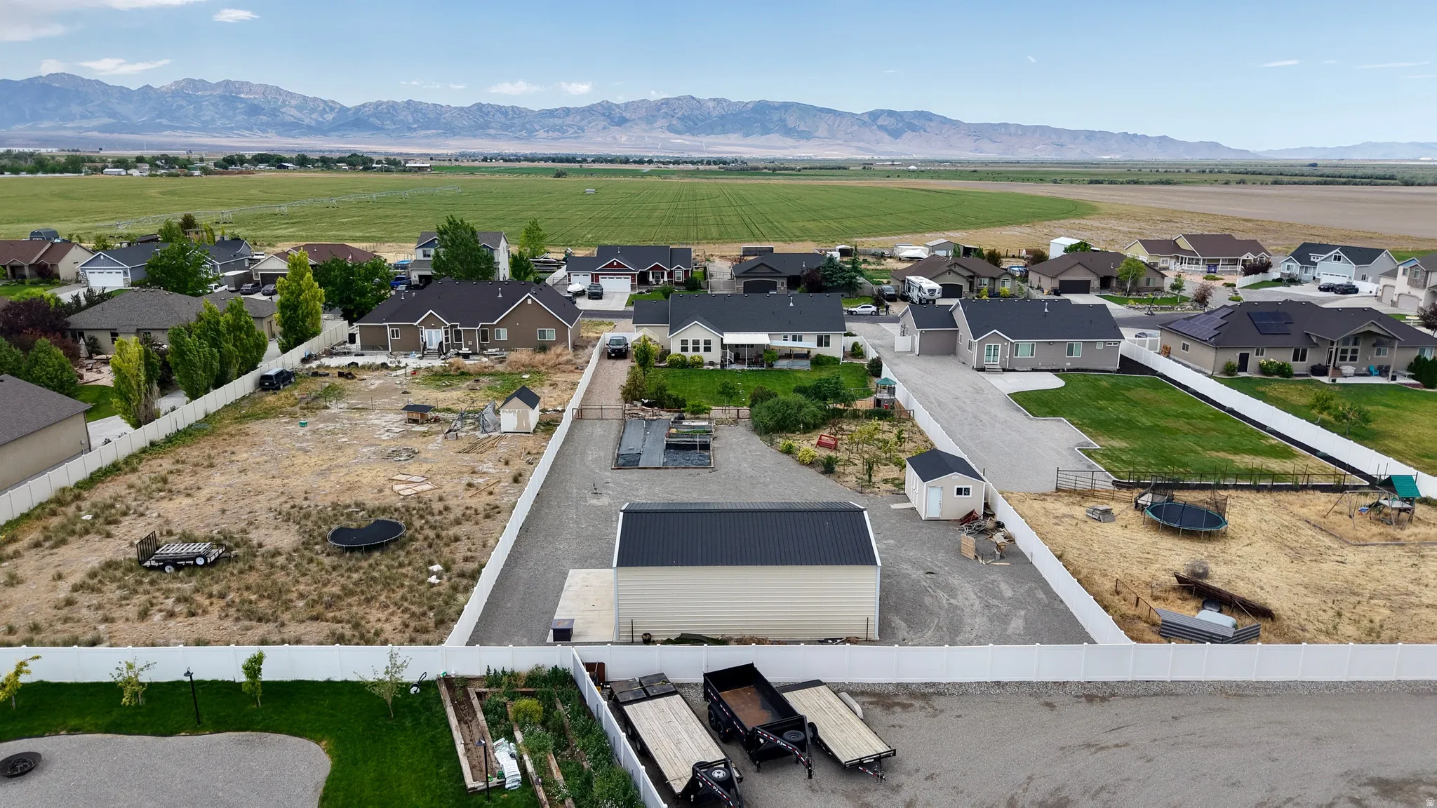 Expansive property featuring a large open lot, a newly constructed outbuilding with a dark metal roof, and a gravel driveway