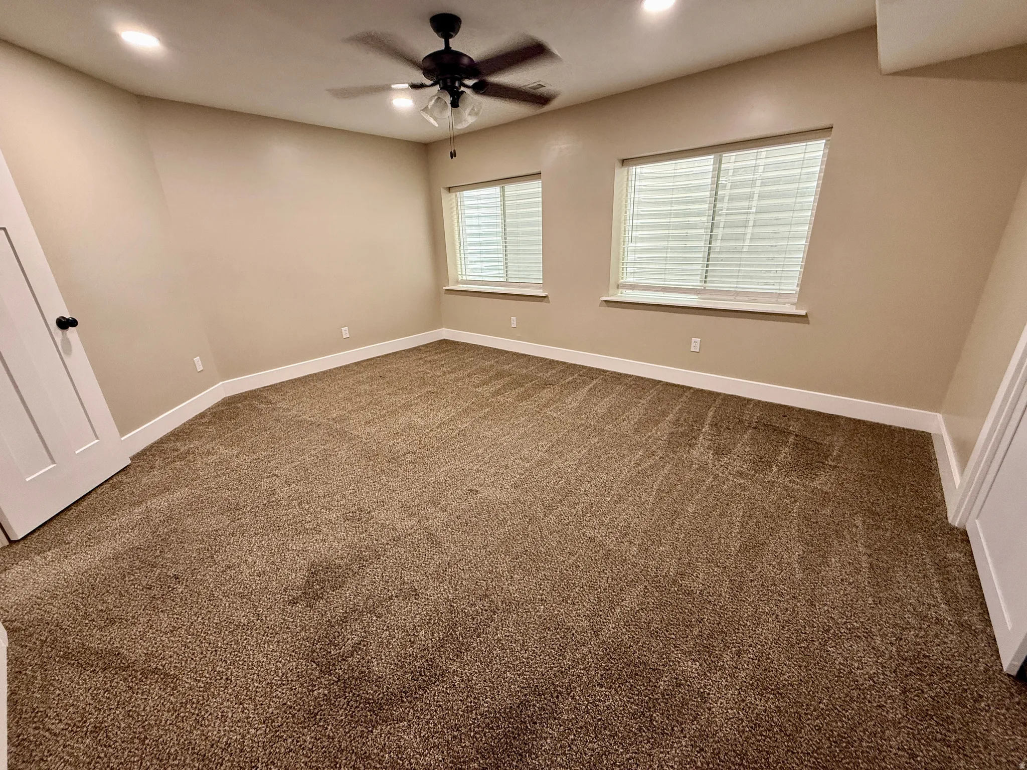 Spacious room featuring neutral-toned walls and plush brown carpeting