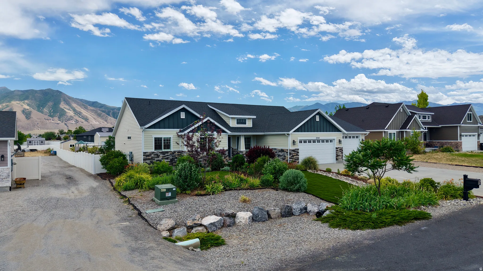 Contemporary single-story residence featuring a two-car garage, partial stone facade, and dark roof shingles