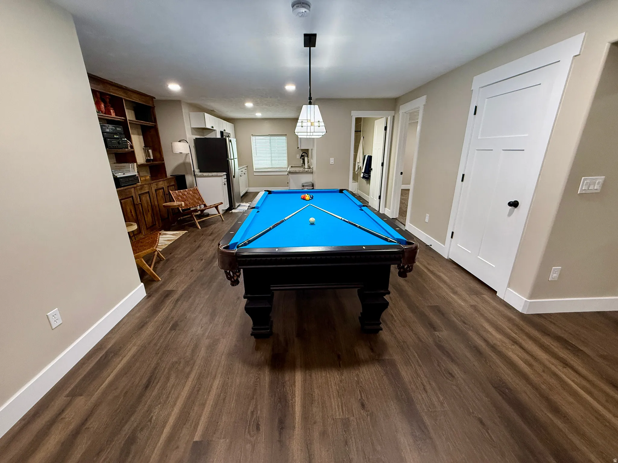 Spacious recreation area featuring wood-finish flooring, a built-in wooden entertainment center, and recessed lighting