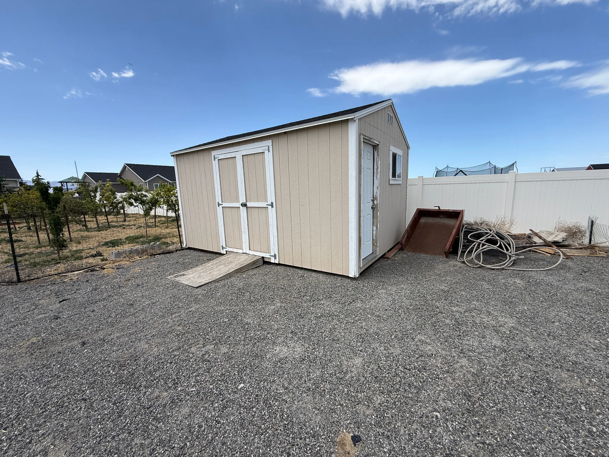 Outdoor storage shed featuring vertical siding, a main double-door entry with ramp, a side door, and a single window