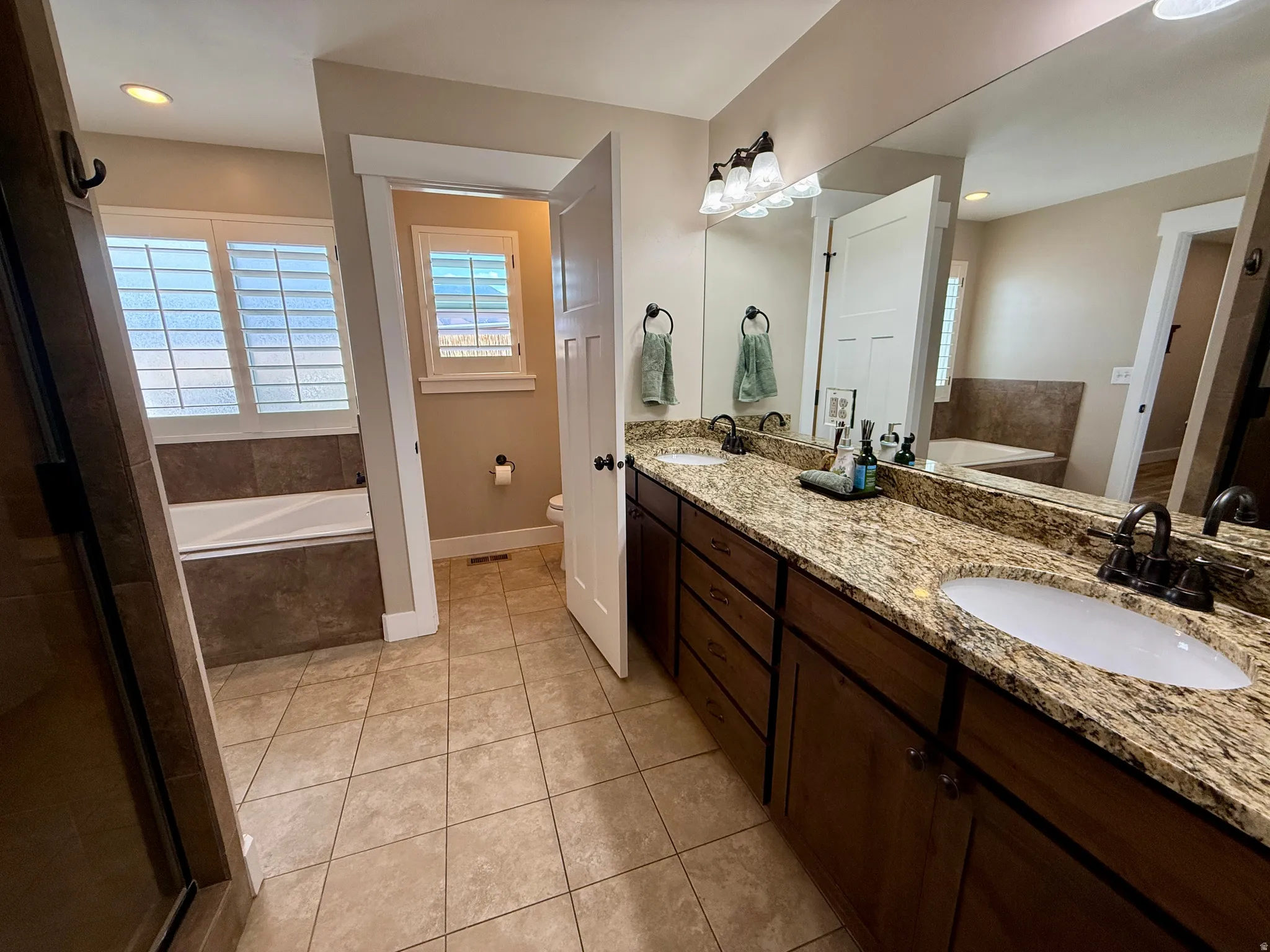 Bathroom featuring a double vanity with stone countertops, individual sinks, and dark wood cabinetry