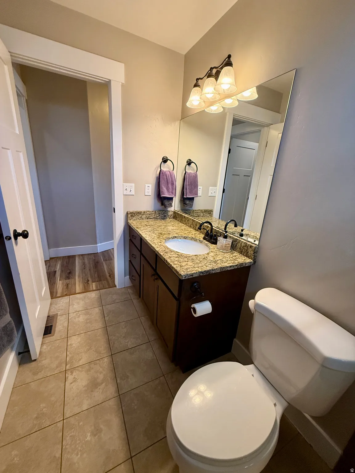 Bathroom featuring a dark wood-finish vanity with a granite countertop, undermount sink, and a large wall-mounted mirror