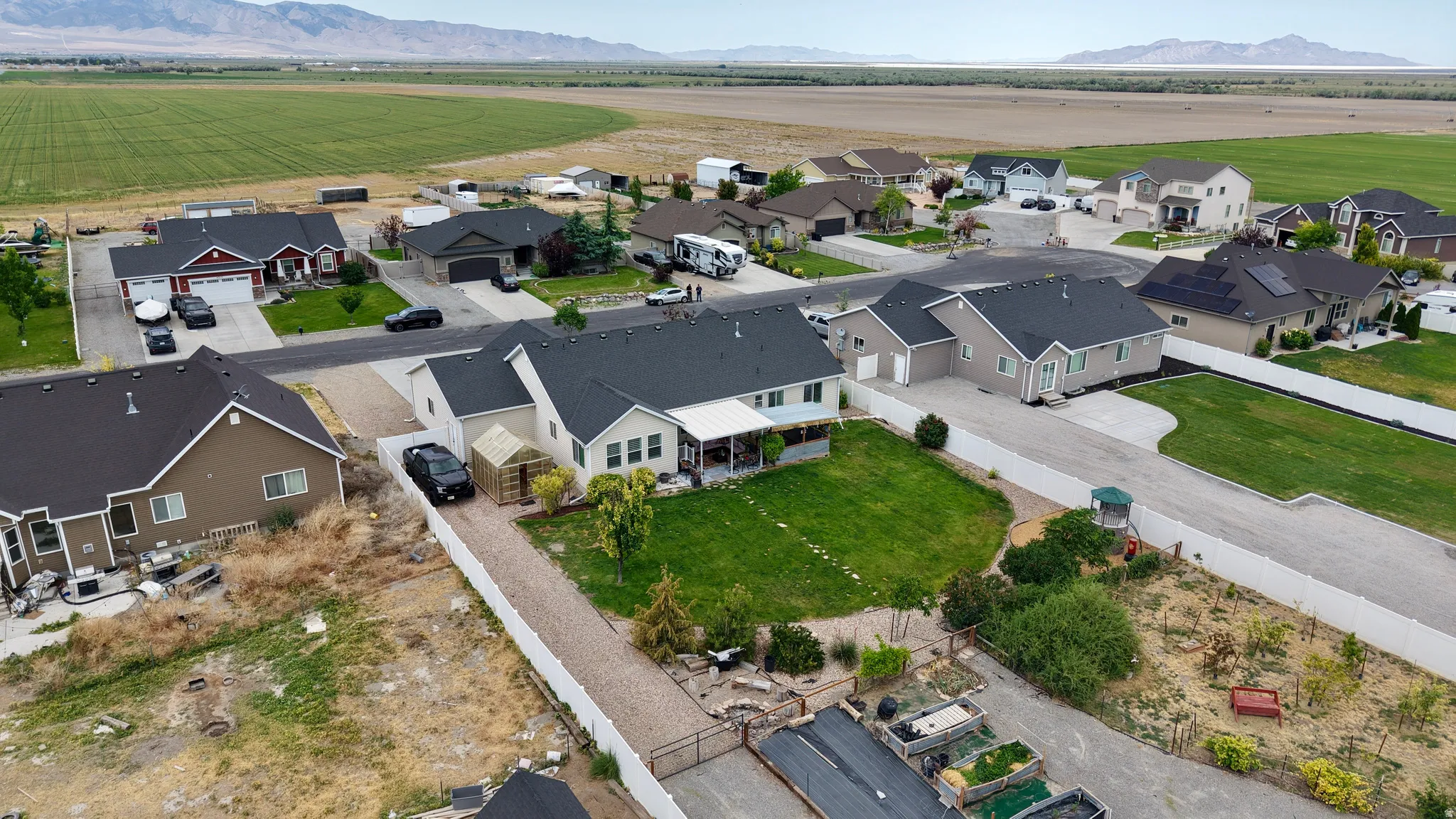 Aerial perspective showcasing a residential neighborhood with surrounding agricultural fields and distant mountains