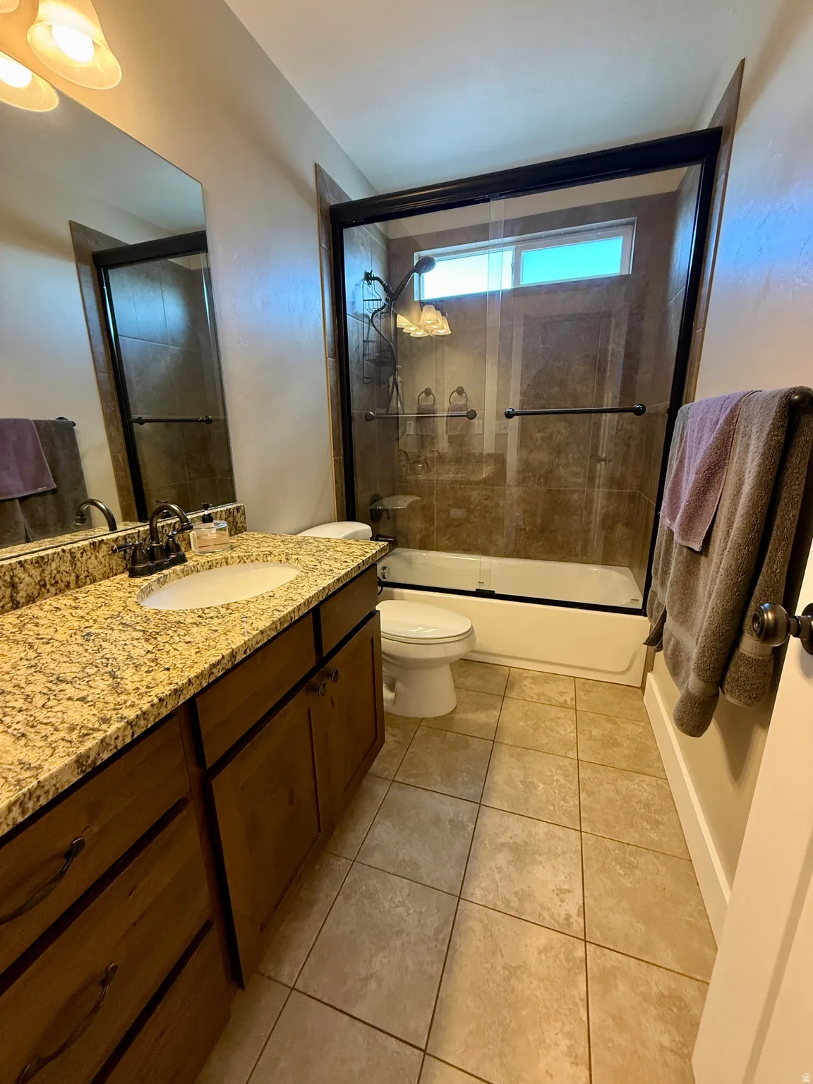 Bathroom featuring a wood-finish vanity with an oval undermount sink and a light-toned speckled countertop