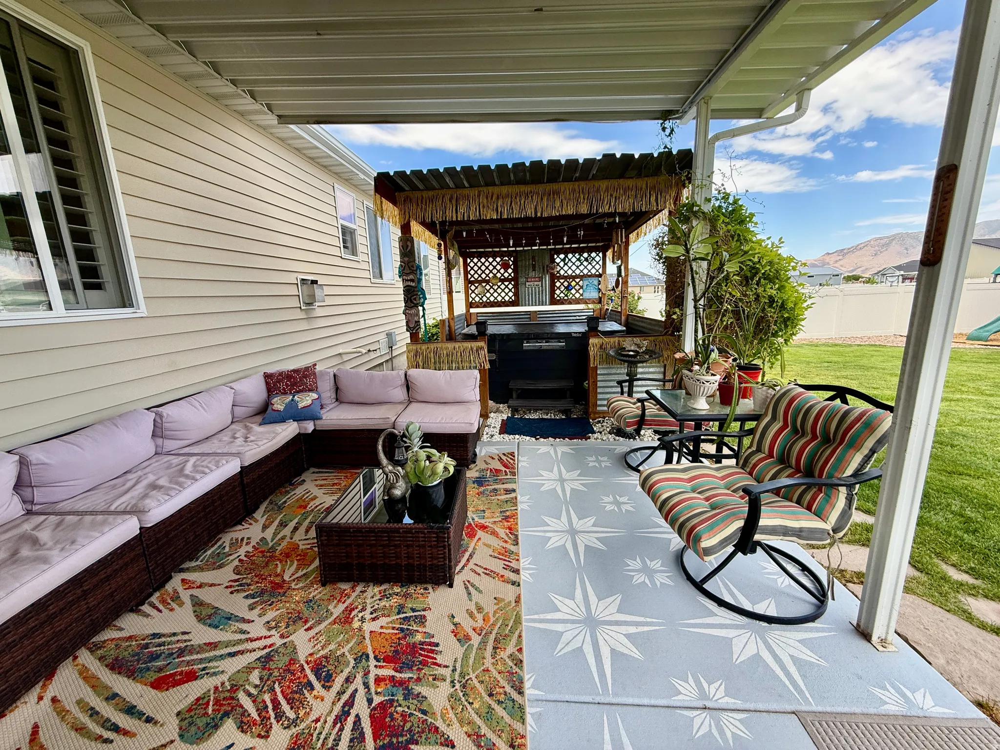 Covered patio featuring an outdoor kitchen area with a built-in grill, corrugated metal paneling, and a thatched roof pergola