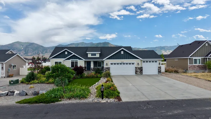 Contemporary ranch-style residence featuring a two-tone exterior with light siding and dark gables, stone accents, and a dark shingle roof