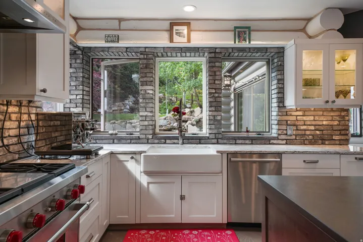 Kitchen featuring white cabinetry, brick backsplash, and light-toned countertops