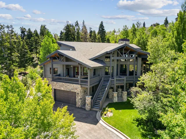 Mountain modern residence featuring extensive stone accents, a multi-level deck, and a prominent chimney