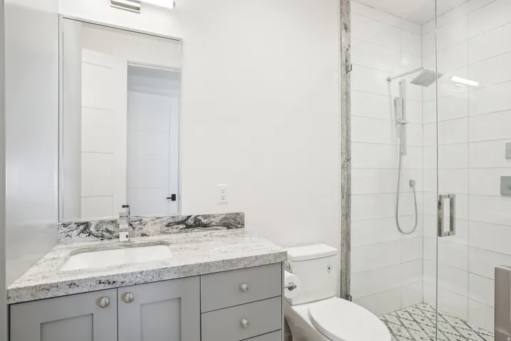 Bathroom featuring a gray vanity with an undermount sink and a light-toned, veined countertop