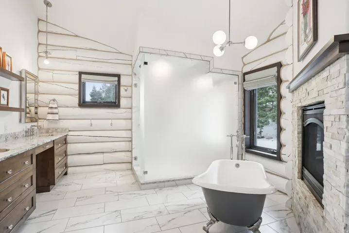 Freestanding clawfoot tub and a glass-enclosed shower complement the white log walls