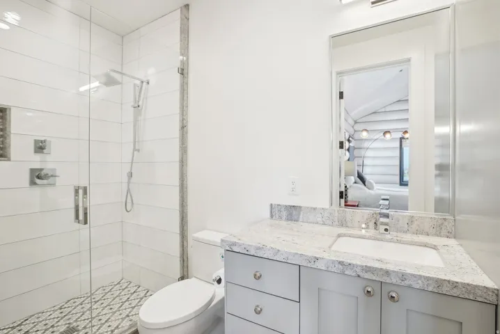 Bathroom featuring a glass-enclosed shower with white subway tile, a decorative mosaic tile shower floor, and a built-in shower niche