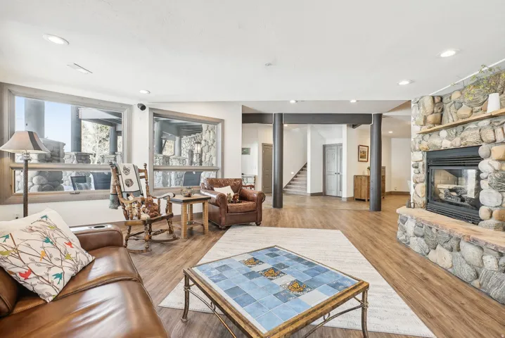 Spacious living area featuring a prominent stone fireplace with a stone hearth and mantel