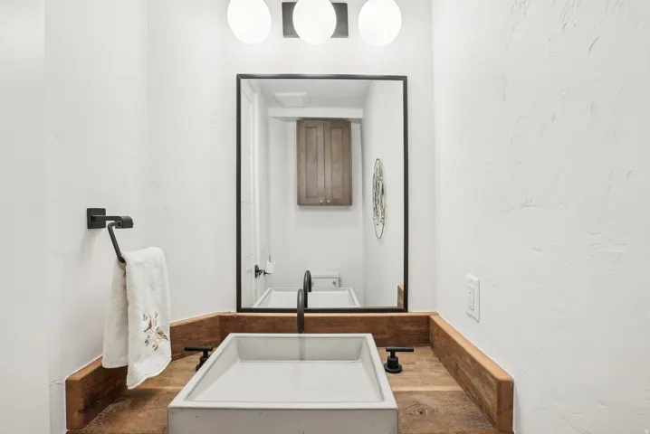 Powder room featuring a concrete vessel sink, matte black faucet, and a rustic wood countertop