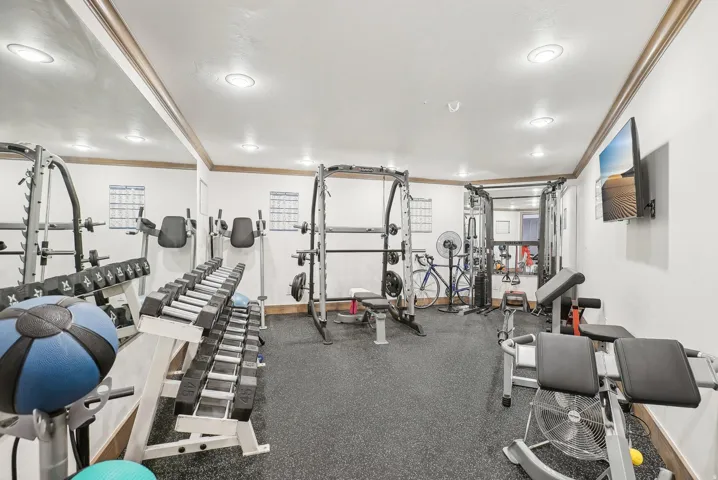 Dedicated fitness space featuring rubber flooring and mirrored wall