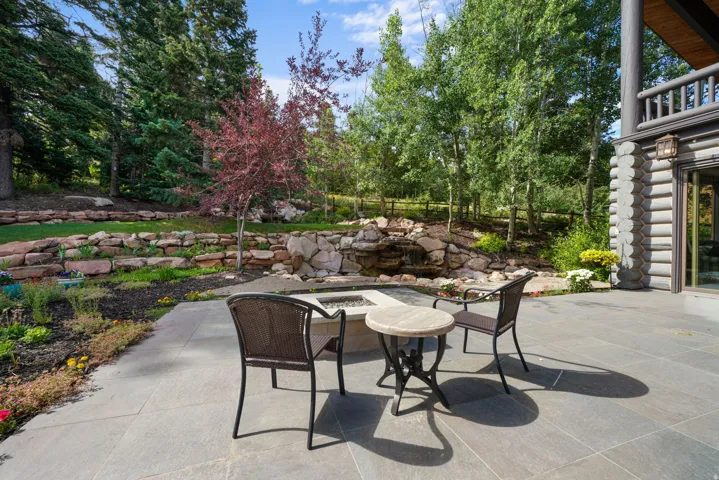 Spacious patio featuring stone-finish pavers and a built-in fire pit