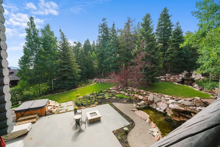 Expansive outdoor living area featuring a stone patio, built-in fire pit, and integrated hot tub