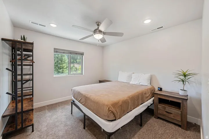 Carpeted room featuring a ceiling fan with integrated lighting, recessed lighting, and a window providing natural illumination