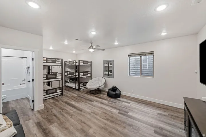 Spacious room featuring wood-finish flooring, recessed lighting, and a ceiling fan