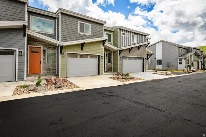 Contemporary townhomes featuring varied siding finishes, attached garages, and distinctive architectural details