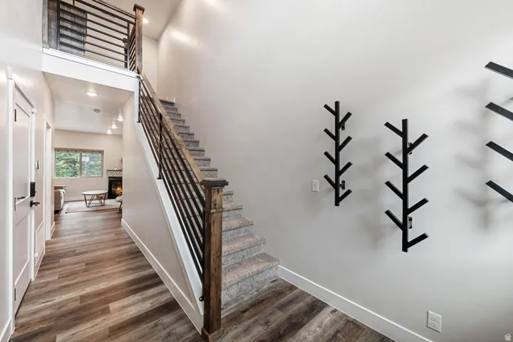 Open entry hall featuring wood-finish flooring, a carpeted staircase with wood newel posts, and a contemporary metal railing