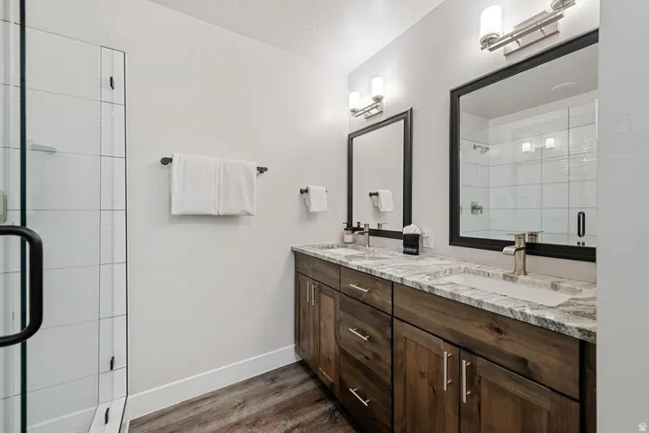 Bathroom featuring a dual vanity with wood-finish cabinetry and light-toned countertops