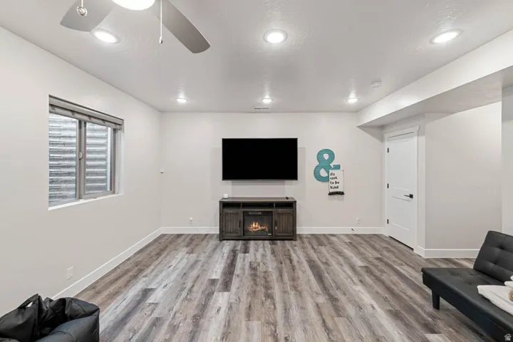 Spacious room featuring wood-finish flooring, recessed lighting, and a modern ceiling fan