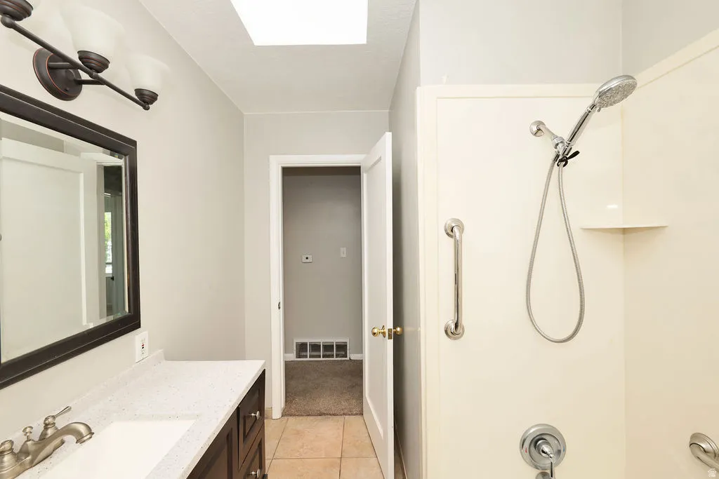 Bathroom featuring a vanity with a white speckled countertop, dark wood-finish cabinetry, a rectangular undermount sink, and a brushed nickel faucet