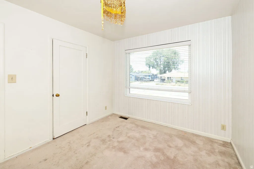 Room featuring light-colored carpet, a large window with blinds, and striped wallpaper on one wall