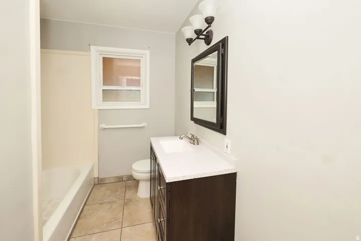 Bathroom featuring a dark wood-finish vanity with a light-toned countertop, an integrated sink, and brushed nickel fixtures