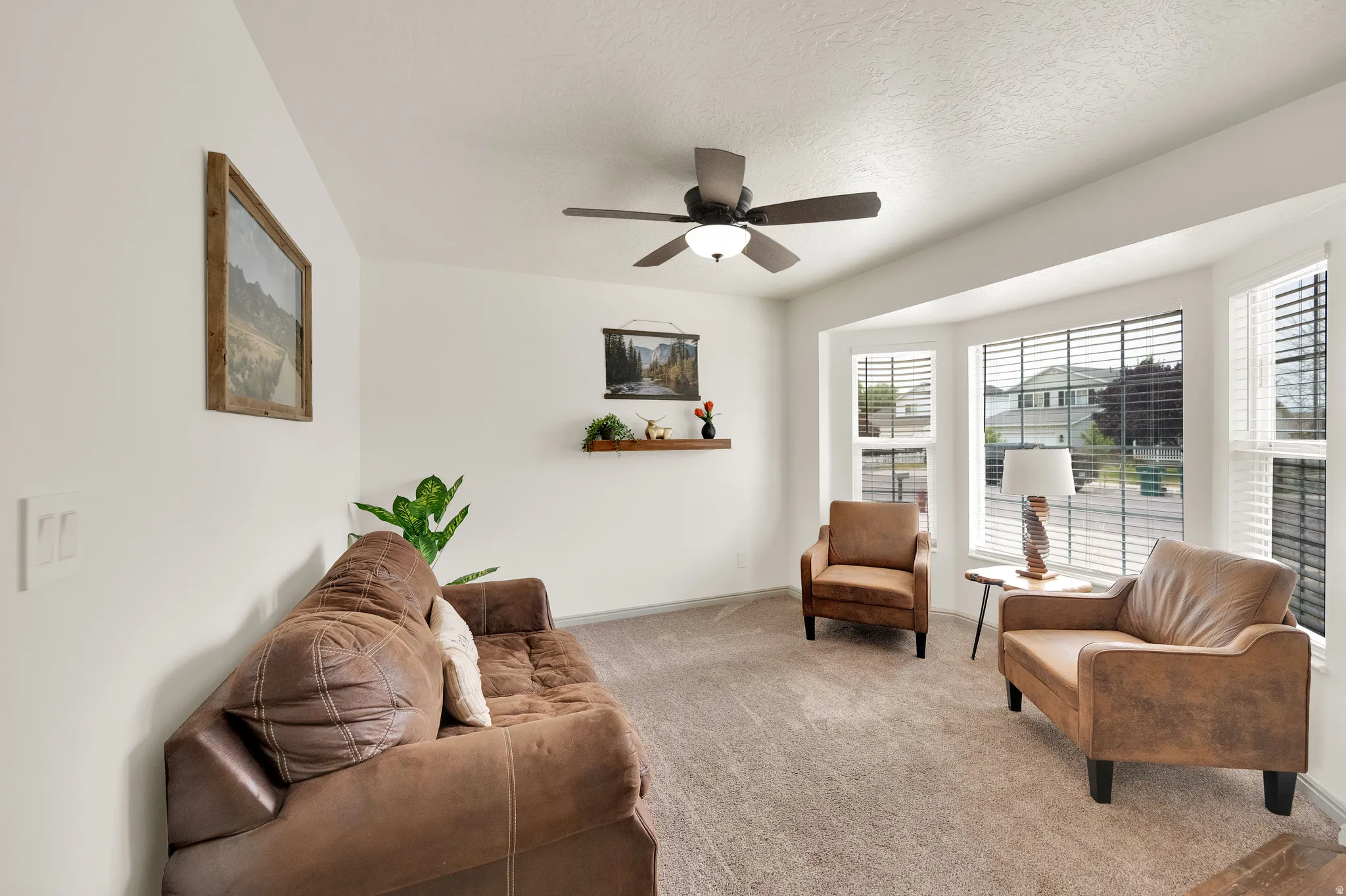 Front living room featuring a bay window and ceiling fan.