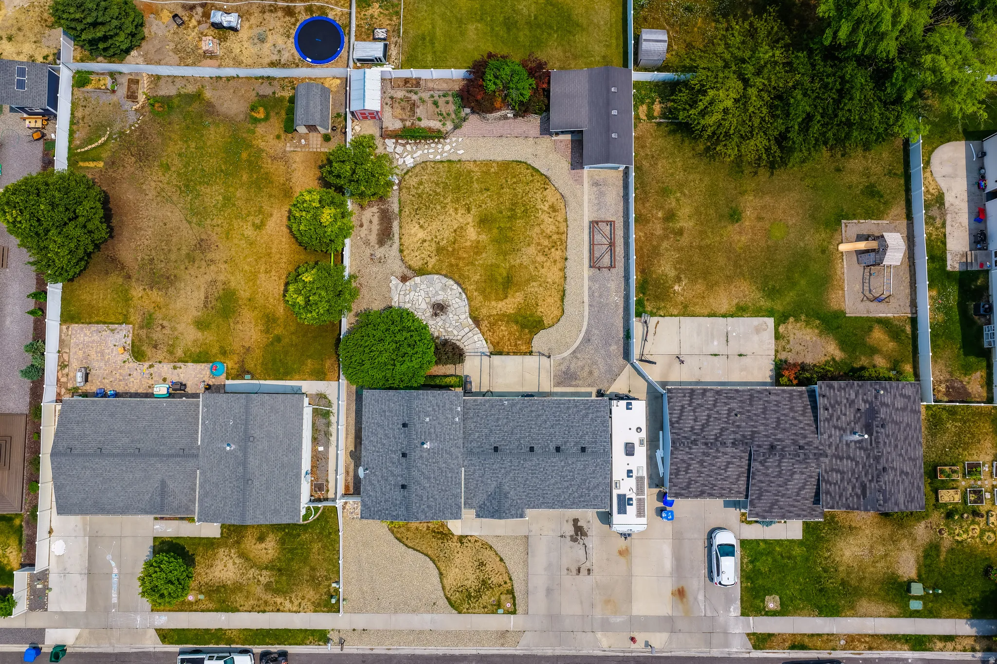 Expansive lot featuring two distinct lawn areas, mature trees, and a paved stone pathway