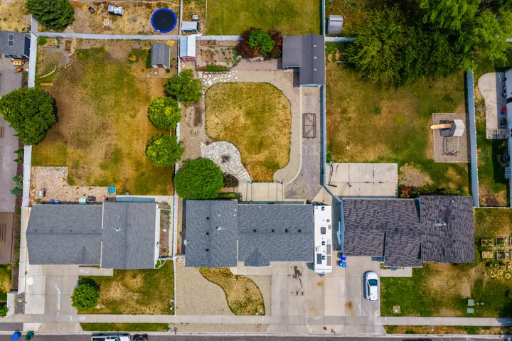 Expansive lot featuring two distinct lawn areas, mature trees, and a paved stone pathway