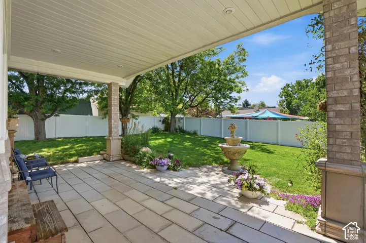 Covered patio with large format stone pavers, brick-clad columns, and a tiered fountain