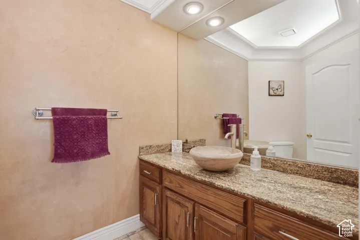 Vanity with stone countertop and vessel sink, wood cabinetry, and an integrated wall mirror