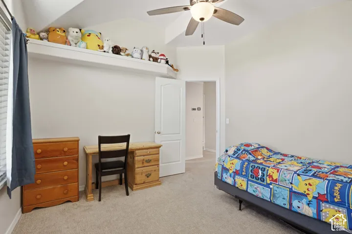 Carpeted room with a ceiling fan, sloped ceiling, and white painted walls