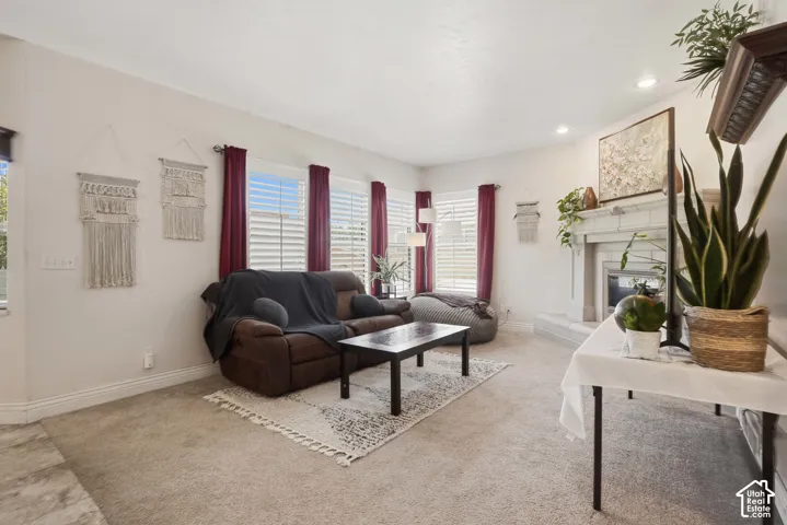 Living area featuring a fireplace with a detailed mantel, recessed lighting, and multiple windows with horizontal blinds