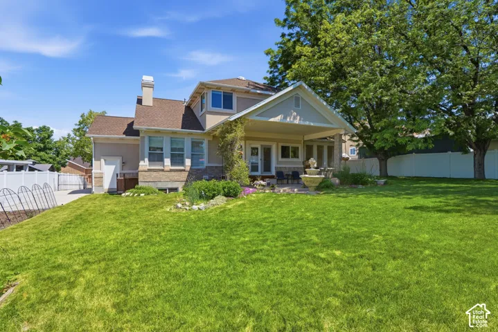 Expansive green lawn with mature trees and a white privacy fence
