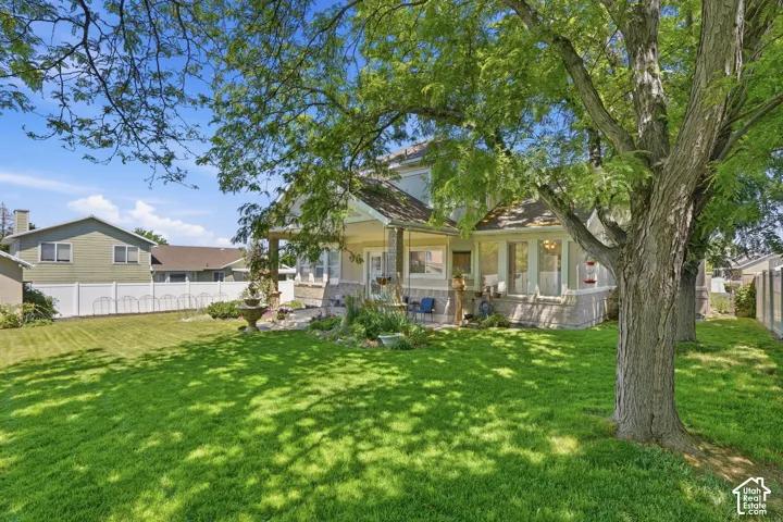 Expansive lawn area featuring mature trees and a white privacy fence