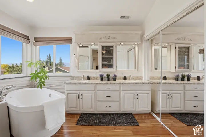 Dual vanity with granite countertops, decorative mirrors, and recessed lighting