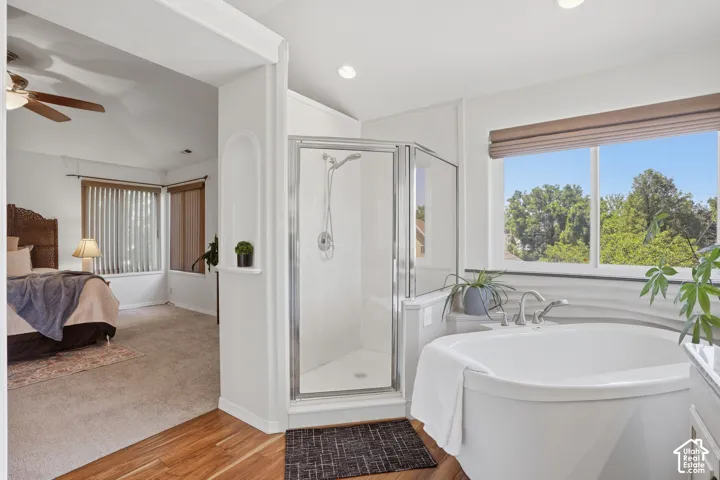 Stand-alone soaking tub with a large window, glass-enclosed shower, and recessed lighting