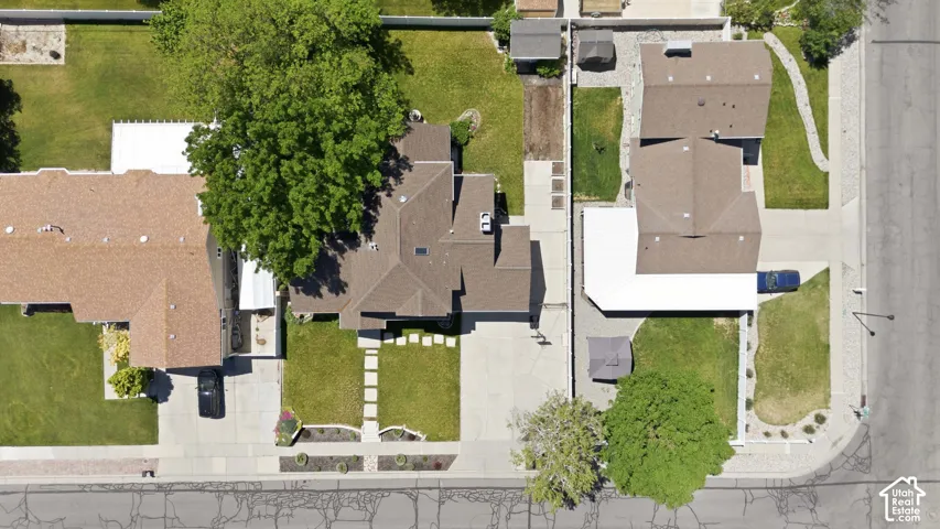Aerial perspective showcasing a property with a gabled roofline, concrete driveway, and a spacious green lawn