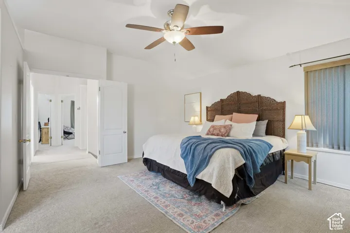 Spacious room featuring vaulted ceilings, recessed window with vertical blinds, and light-toned carpeting