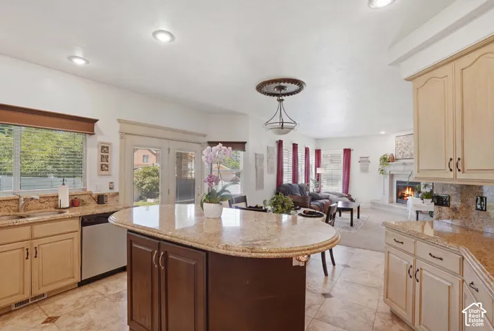 Kitchen with light-toned cabinetry and granite countertops, featuring a central island with an extended counter