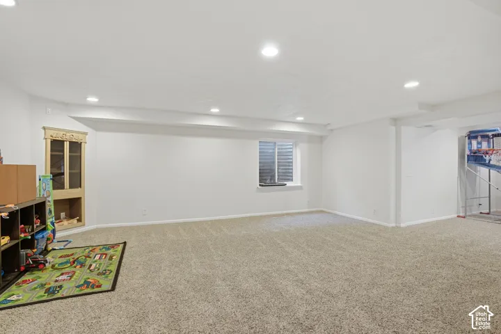 Expansive lower-level space featuring neutral carpeting, recessed lighting, and a white color palette throughout