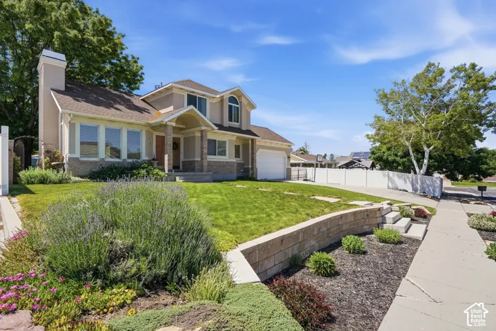 Two-story residence featuring a covered entry, an attached two-car garage, and a stucco and stone exterior