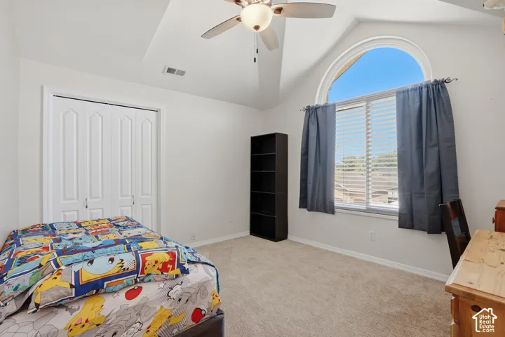 Carpeted room featuring a large arched window, ceiling fan, bi-fold closet doors, and tray ceiling detail