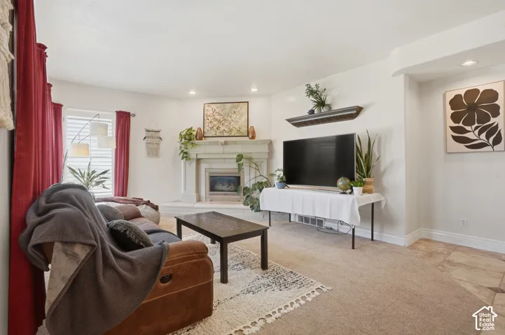 Living area featuring a gas fireplace with a stone surround and mantel, recessed lighting, and mixed flooring with carpet and tile